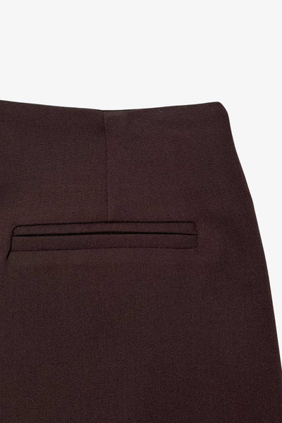 Falda short de fit ajustado, cintura alta, cruce frontal asimétrico, vivos decorativos posteriores y cierre lateral con cremallera oculta.