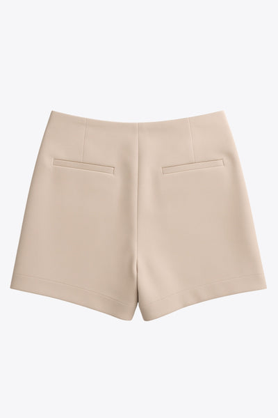 Falda short corto de fit ajustado, cintura alta, cruce frontal con nudo y plisados decorativos frontales. Cierre posterior con cremallera oculta.