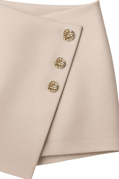 Falda short corto de fit ajustado, cintura alta, cruce frontal con nudo y plisados decorativos frontales. Cierre posterior con cremallera oculta.