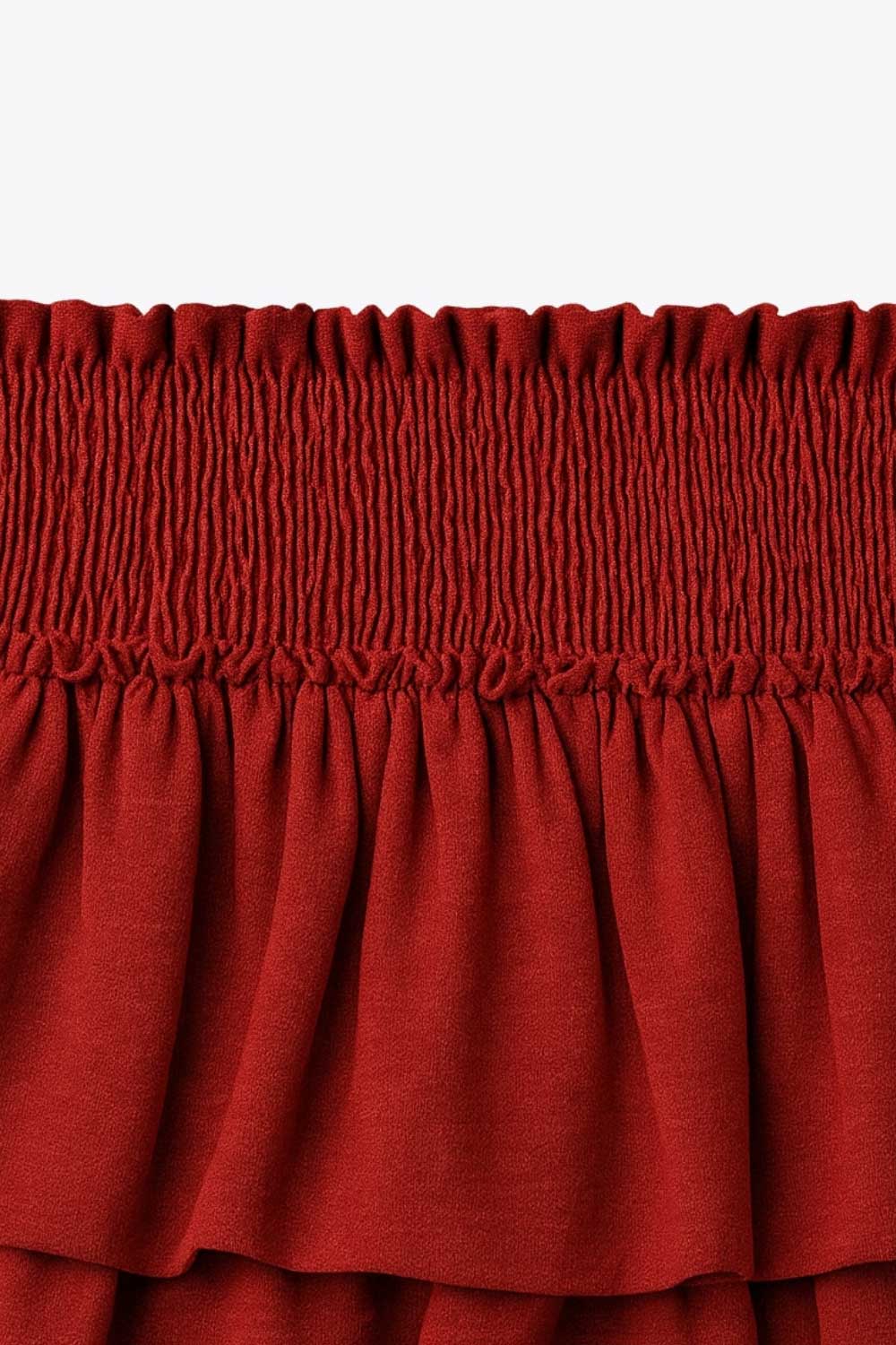 Falda short de corte en a, cintura alta elástica con pretina fruncida y capas de olanes en bajo.