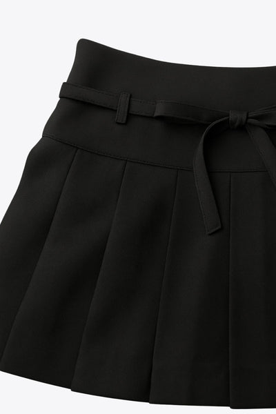 Falda short corto tableado, de corte en a, cintura alta con pretina, trabillas y lazo amarrable del tejido. Detalle de tableado en bajo y cierre lateral con cremallera oculta.