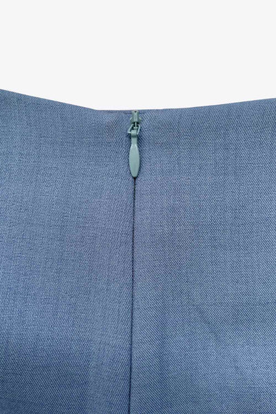 Falda short corto de fit ajustado, cintura alta, cruce frontal con nudo y plisados decorativos frontales. Cierre posterior con cremallera oculta.