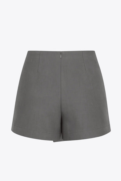 Falda short corto de fit ajustado, cintura alta, cruce frontal con nudo y plisados decorativos frontales. Cierre posterior con cremallera oculta.