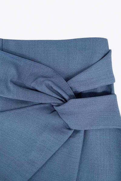 Falda short corto de fit ajustado, cintura alta, cruce frontal con nudo y plisados decorativos frontales. Cierre posterior con cremallera oculta.