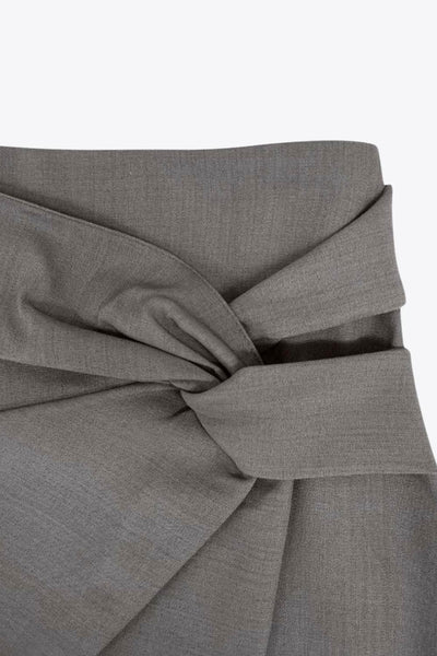 Falda short corto de fit ajustado, cintura alta, cruce frontal con nudo y plisados decorativos frontales. Cierre posterior con cremallera oculta.