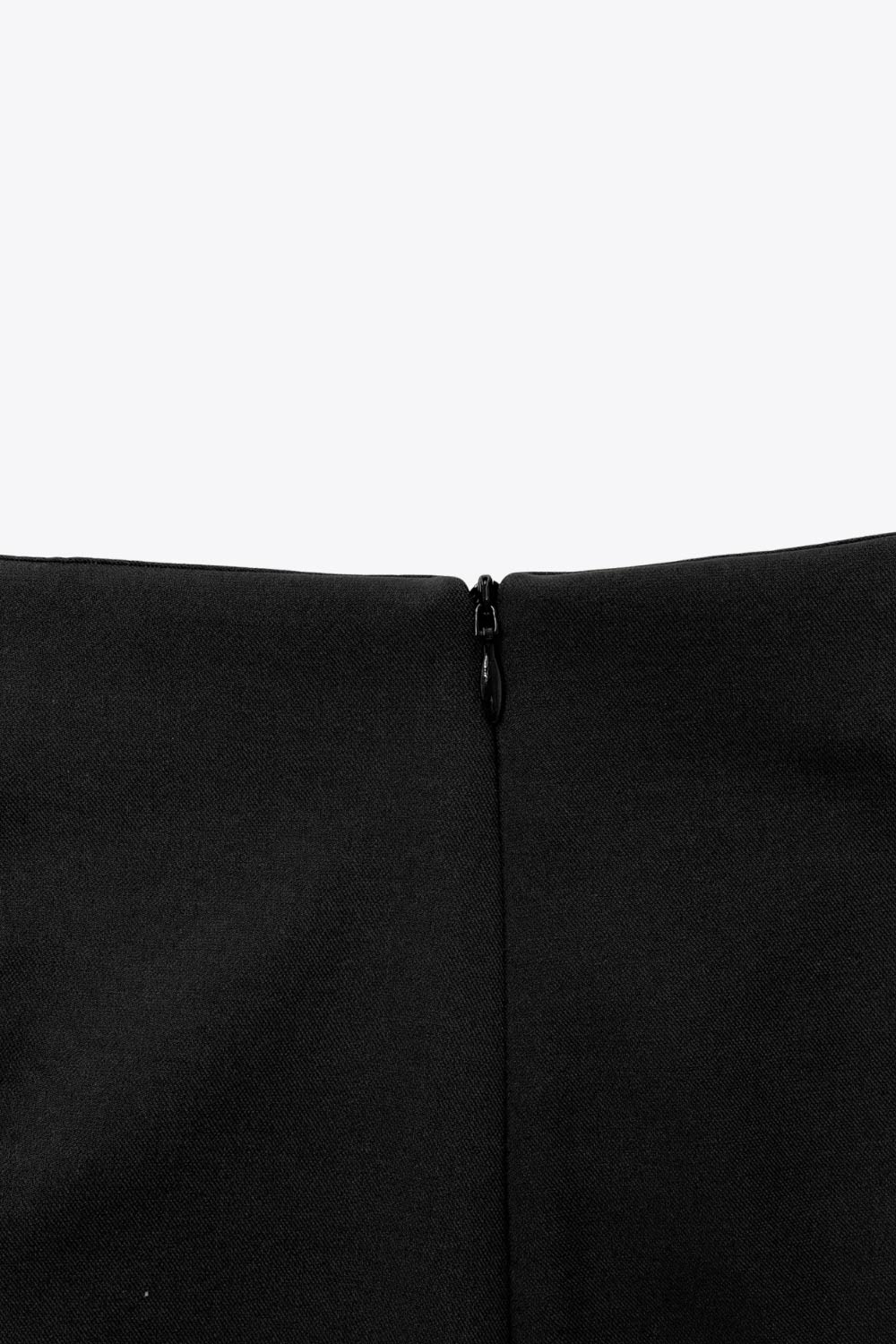 Falda short corto de fit ajustado, cintura alta, cruce frontal con nudo y plisados decorativos frontales. Cierre posterior con cremallera oculta.