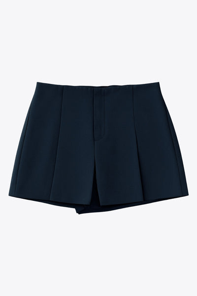 Falda short corto de cintura alta con pinzas y tableado frontal, corte en a, vivos decorativos posteriores y cierre lateral con cremallera oculta.