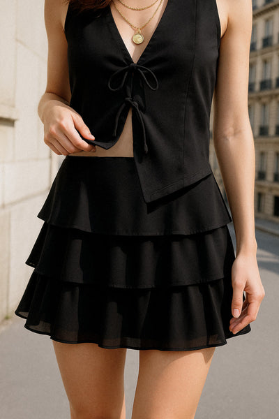 Falda short corto de cintura alta, corte en a, capas de olanes y cierre lateral con cremallera oculta.