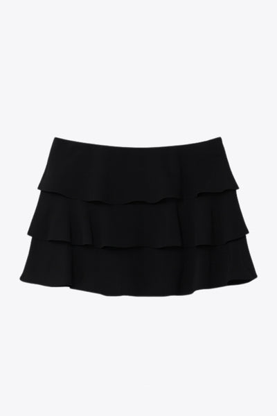 Falda short corto de cintura alta, corte en a, capas de olanes y cierre lateral con cremallera oculta.