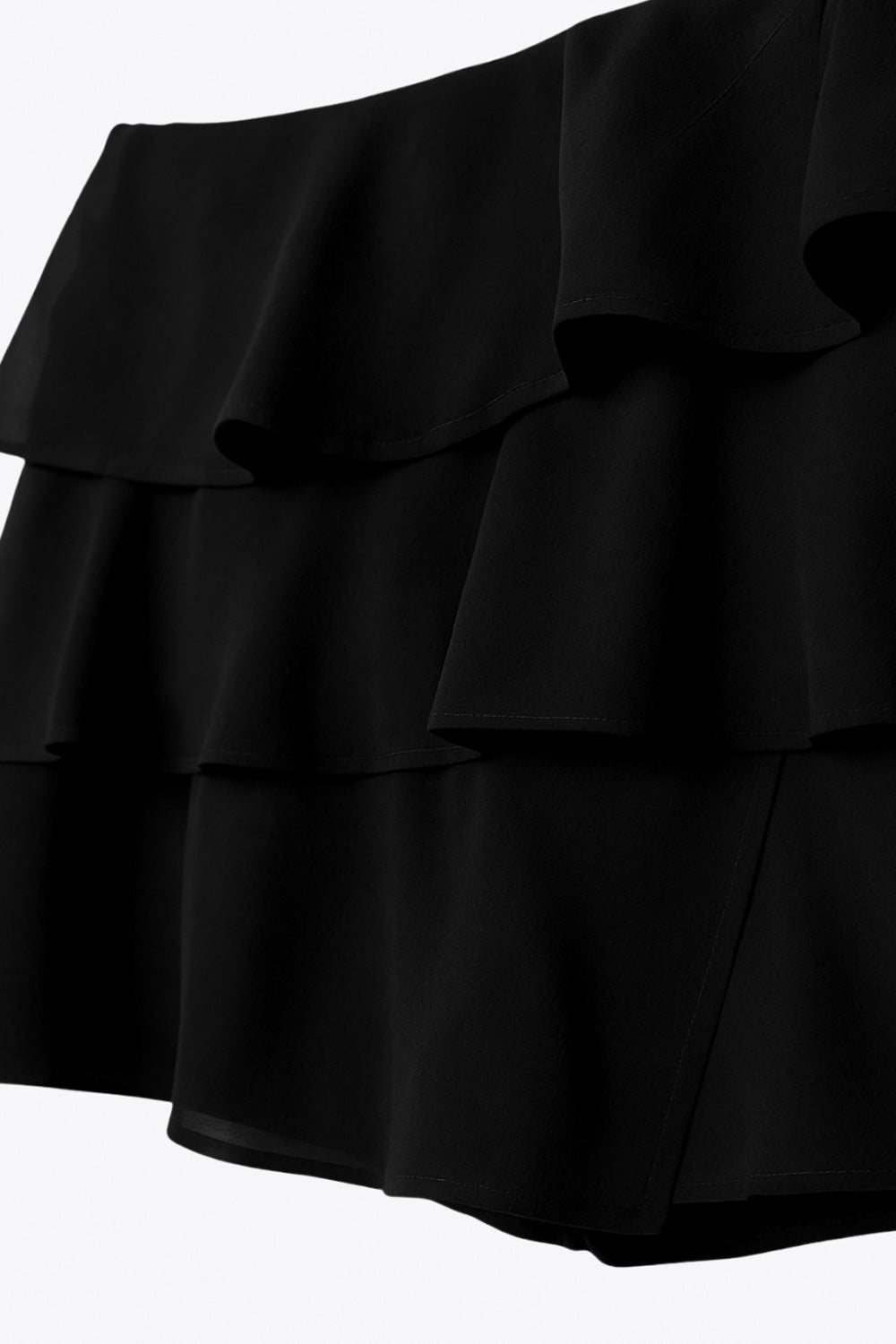 Falda short corto de cintura alta, corte en a, capas de olanes y cierre lateral con cremallera oculta.