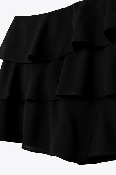 Falda short corto de cintura alta, corte en a, capas de olanes y cierre lateral con cremallera oculta.