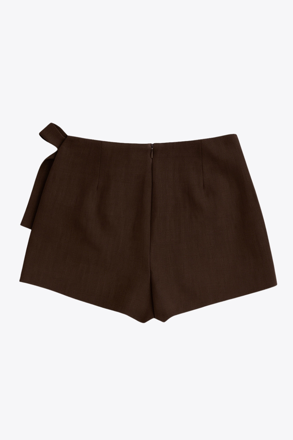 Falda short corto de cintura alta, corte en a, sobrefalda con cruce frontal, lazo lateral amarrable y cierre posterior con cremallera oculta.