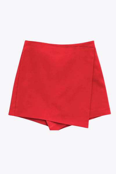 Falda short corto de fit ajustado, cintura alta, cruce frontal con bajo asimétrico, vivos decorativos posterior y cierre lateral con cremallera oculta.