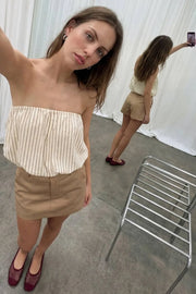 Falda short corto satinado de fit recto, cintura alta con pretina, trabillas, bolsillos delanteros, cierre frontal con broche y cremallera ocultos.