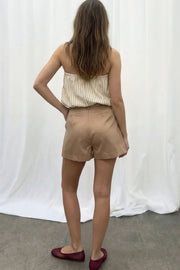 Falda short corto satinado de fit recto, cintura alta con pretina, trabillas, bolsillos delanteros, cierre frontal con broche y cremallera ocultos.