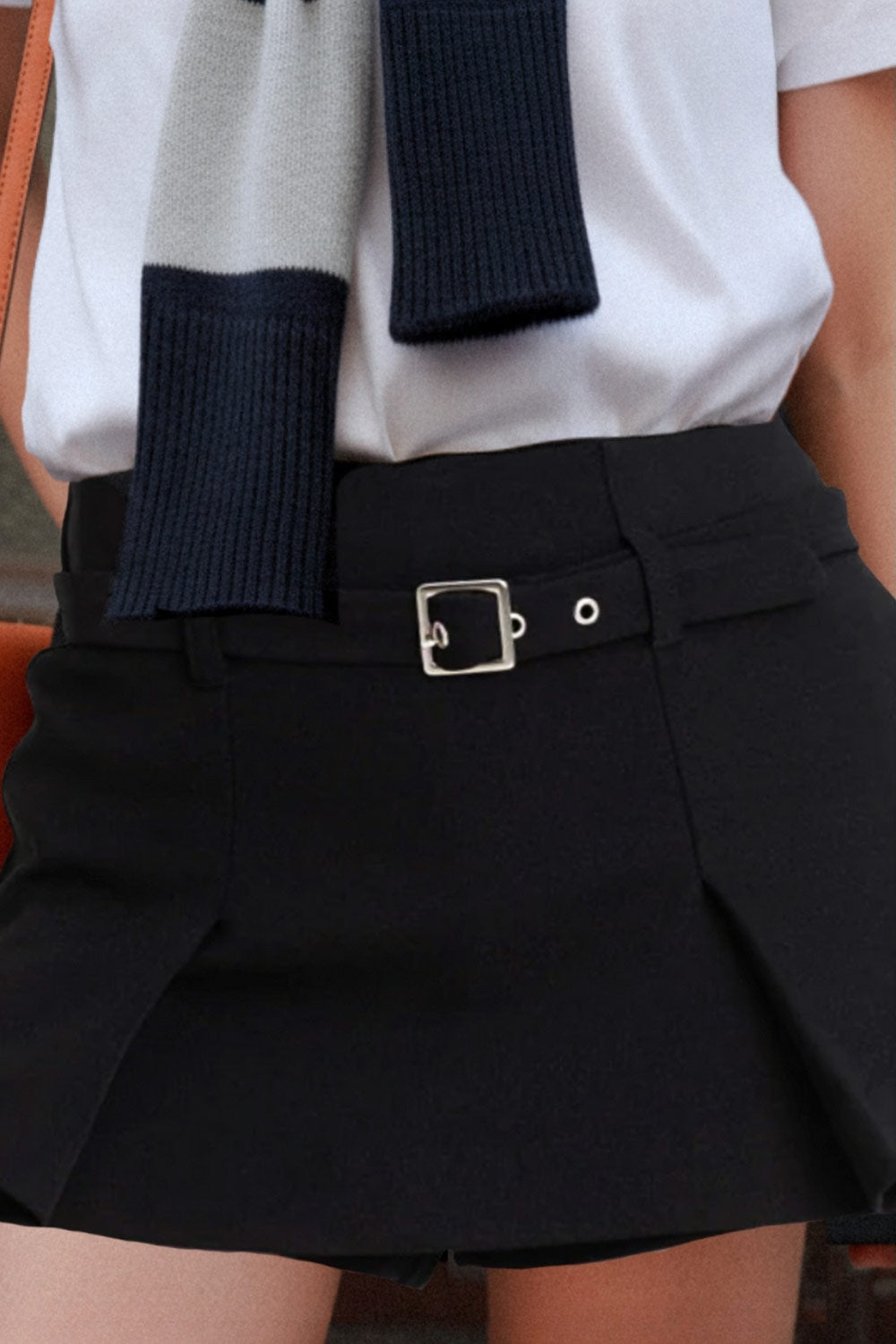 Falda short corto tableado, de cintura media, trabillas y cinturón con hebilla en contraste. Cierre lateral con cremallera oculta.