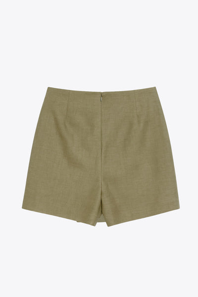 Falda short de fit ajustado, cintura alta, nudo frontal con plisados decorativos y bajo asimétrico. Cierre posterior con cremallera oculta.