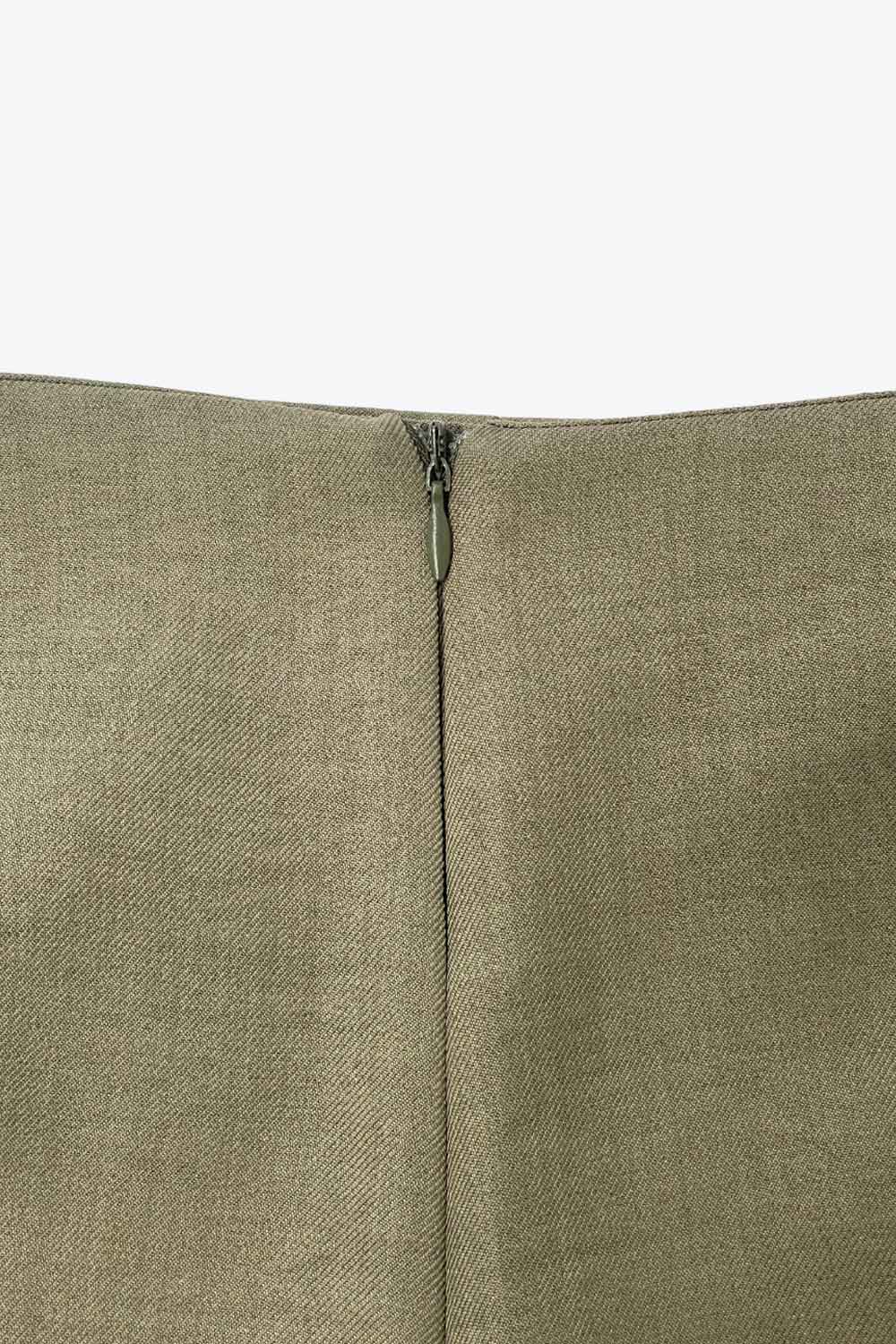 Falda short de fit ajustado, cintura alta, nudo frontal con plisados decorativos y bajo asimétrico. Cierre posterior con cremallera oculta.