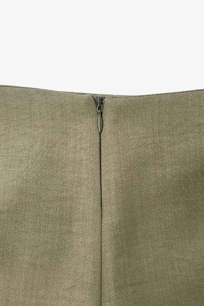 Falda short de fit ajustado, cintura alta, nudo frontal con plisados decorativos y bajo asimétrico. Cierre posterior con cremallera oculta.