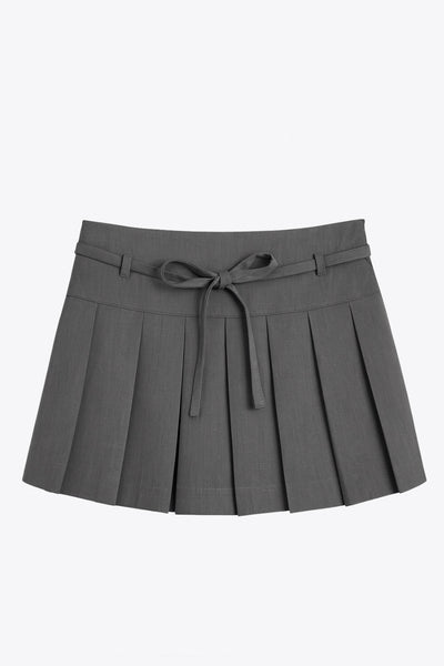 Falda short corto tableado, de corte en a, cintura alta con pretina, trabillas y lazo amarrable del tejido. Detalle de tableado en bajo y cierre lateral con cremallera oculta.