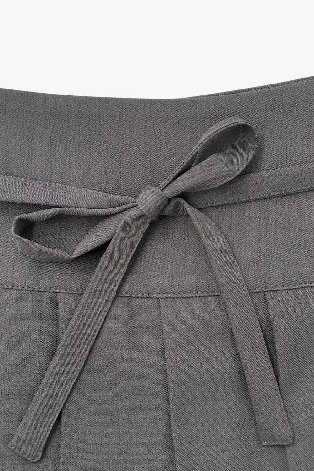 Falda short corto tableado, de corte en a, cintura alta con pretina, trabillas y lazo amarrable del tejido. Detalle de tableado en bajo y cierre lateral con cremallera oculta.