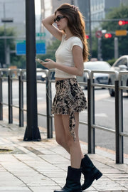Falda short corto de mesh con estampado floral, cintura alta, corte en a, pretina ancha, bajo con capas de olanes y detalle decorativo. Cierre lateral con cremallera oculta.