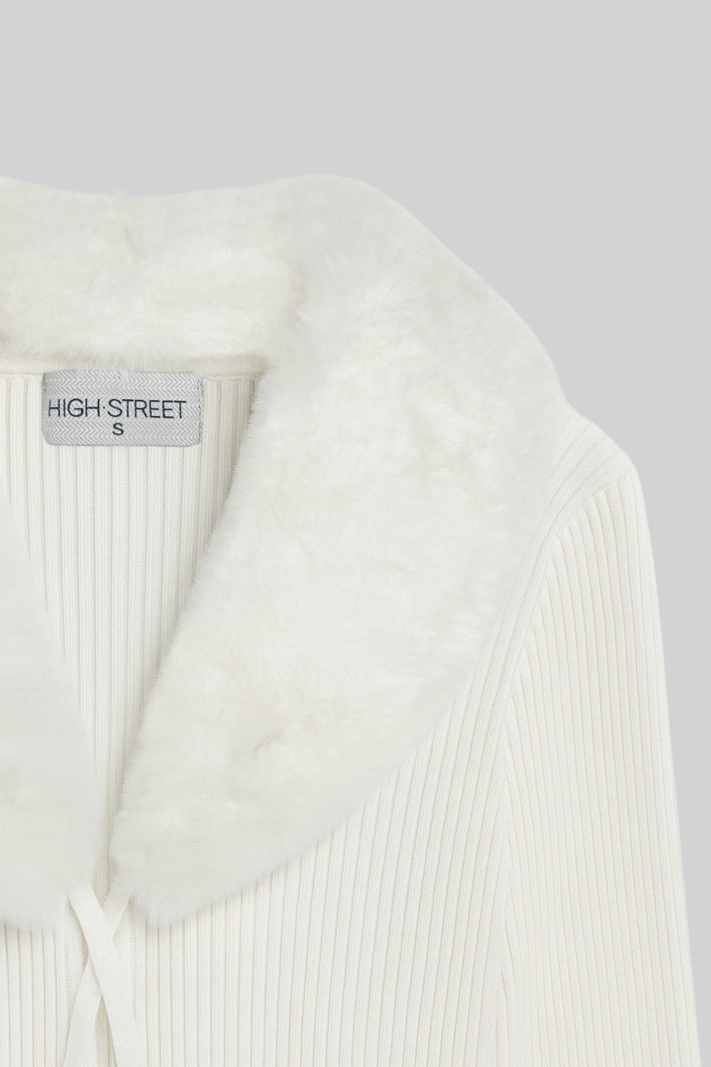 Jersey corto canalé de fit recto, manga larga, cuello v con solapa desmontable de efecto pelo y cierre frontal lazo amarrable.