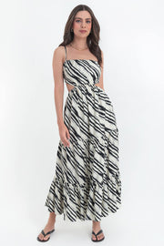 Maxi vestido estampado de corte en a, tirantes delgados ajustables, bajo con capas de olanes, cut out en costados y espalda. Detalle de rib elástico en cintura y cierre lateral con cremallera oculta.
