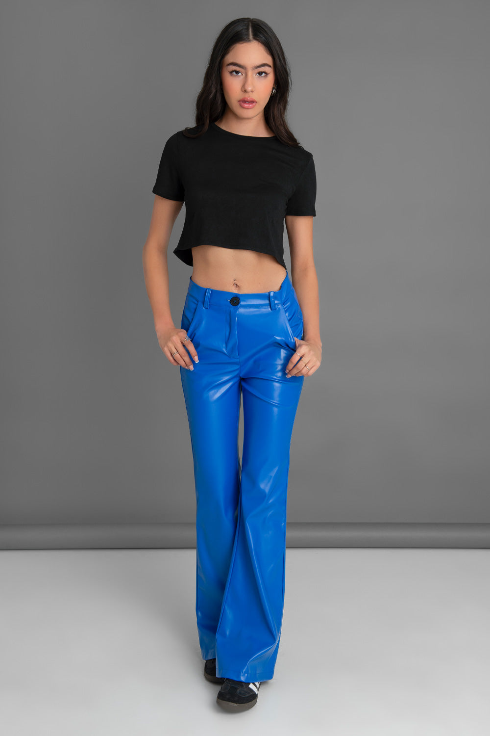 Pantalón ajustado de efecto piel, fit flare, bolsillos delanteros, cintura alta con pretina y trabillas. Cierre frontal con botón en contraste y cremallera oculta.