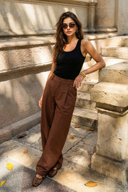 Pantalón de fit wide leg, pinzas frontales, cintura alta con pretina y trabillas, bolsillos delanteros y vivos decorativos traseros. Cierre frontal con broche y cremallera ocultos.