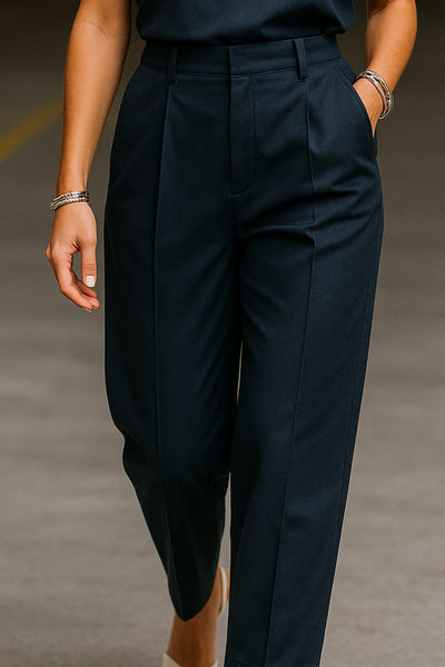 Pantalón de fit wide leg, pinzas frontales, cintura alta con pretina y trabillas, bolsillos delanteros y vivos decorativos traseros. Cierre frontal con broche y cremallera ocultos.