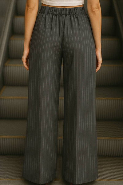 Pantalón de estampado rayas, fit palazzo, cintura alta con pretina elástica posterior, trabillas, bolsillos delanteros y pinzas frontales. Cierre frontal con botón y cremallera oculta.