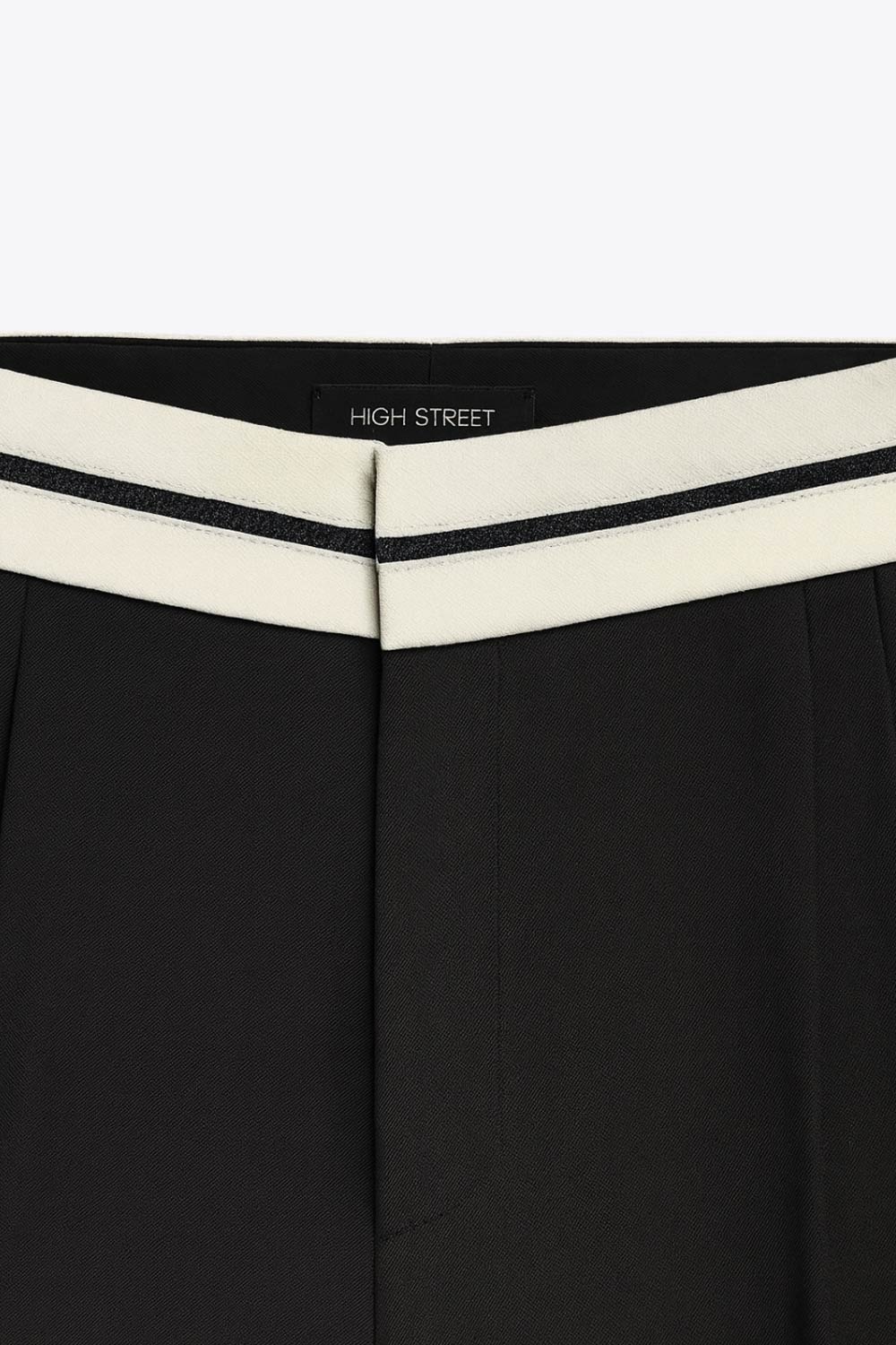 Pantalón de fit wide leg, pinzas frontales, cintura media con detalle de pretina en contraste, bolsillos delanteros y vivos decorativos posteriores. Detalle de raya frontal y posterior. Cierre frontal con broche y cremallera ocultos.