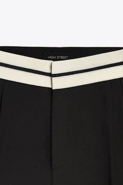 Pantalón de fit wide leg, pinzas frontales, cintura media con detalle de pretina en contraste, bolsillos delanteros y vivos decorativos posteriores. Detalle de raya frontal y posterior. Cierre frontal con broche y cremallera ocultos.