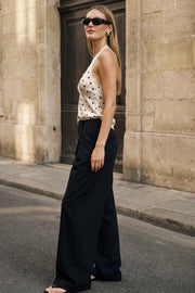 Pantalón de fit palazzo, cintura alta con trabillas, pinzas frontales, bolsillos delanteros y vivos decorativos posteriores, raya frontal y posterior. Cierre frontal con broche y cremallera ocultos.