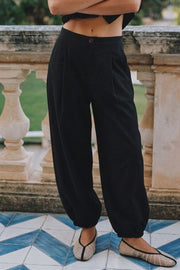 Pantalón fit barrel de cintura media con pretina elástica posterior, bolsillos delanteros, pinzas frontales y rib elástico en bajo. Cierre frontal con botón y cremallera oculta.