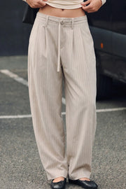 Pantalón de fit balloon, pinzas frontales, estampado rayas, cintura alta con pretina elástica posterior y trabillas, bolsillos delanteros y cinturón amarrable del mismo tejido. Cierre frontal con broche y cremallera ocultos.