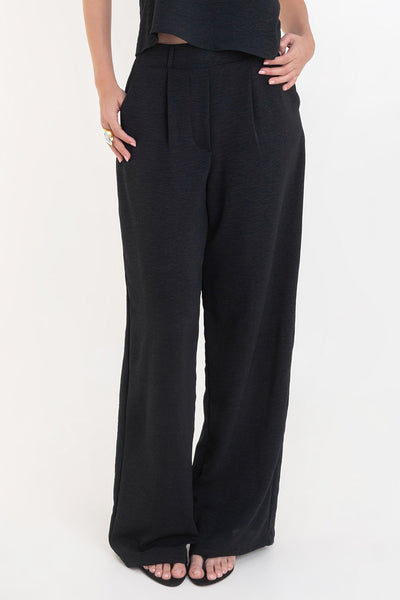 Pantalón de fit palazzo con pierna amplia, pinzas frontales, bolsillos delanteros, cintura alta de pretina con trabillas frontales y elástico posterior.