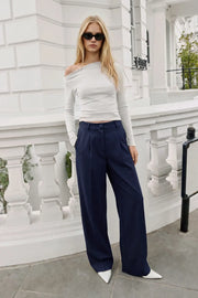 Pantalón de fit wide leg, pinzas frontales, bolsillos delanteros, cintura alta con pretina y trabillas. Detalle de vivo decorativo posterior, cierre con botón y cremallera oculta.