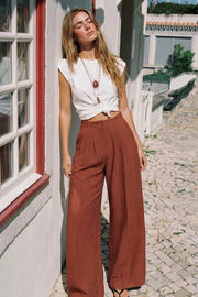 Pantalón fluido de cintura alta con pretina y trabillas, fit wide leg, pinzas frontales, bolsillos delanteros, detalle de raya frontal y posterior. Cierre frontal con botón y cremallera oculta.