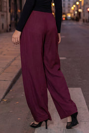 Pantalón fluido de cintura alta con pretina y trabillas, fit wide leg, pinzas frontales, bolsillos delanteros, detalle de raya frontal y posterior. Cierre frontal con botón y cremallera oculta.