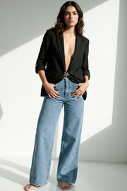 Pantalón de denim, fit recto, cintura alta, pinzas frontales, bolsillos delanteros y traseros de parche. Cierre con botón y cremallera oculta.