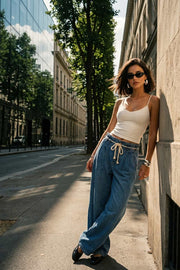 Pantalón de denim, fit wide leg, cintura alta con pretina elástica y trabillas, pinzas frontales, jareta frontal en contraste, bolsillos delanteros y traseros de parche. Cierre frontal con cremallera oculta.