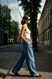 Pantalón de denim, fit wide leg, cintura alta con pretina elástica y trabillas, pinzas frontales, jareta frontal en contraste, bolsillos delanteros y traseros de parche. Cierre frontal con cremallera oculta.