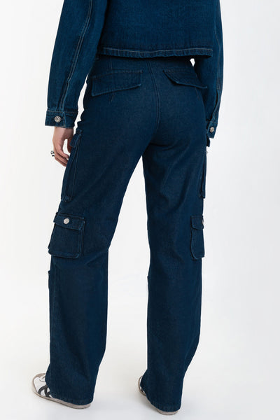 Pantalón de denim multipocket, fit recto, cintura alta con pretina y trabillas, bolsillos delanteros, laterales cargo con cartera y traseros decorativos con cartera. Cierre frontal con cremallera y botón en contraste.