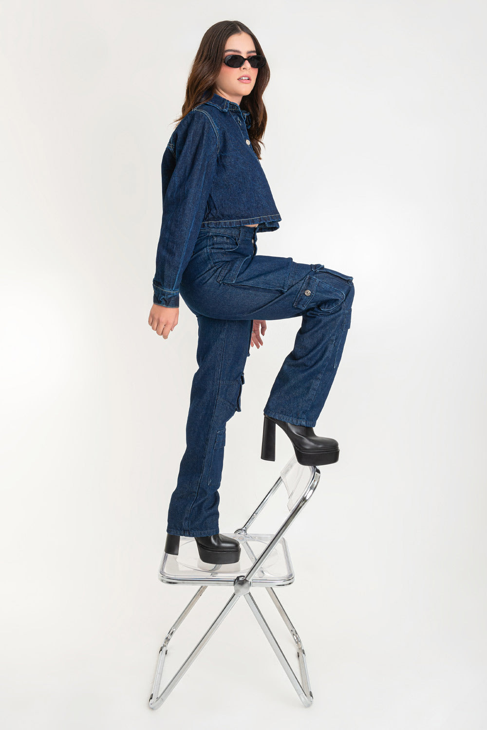 Pantalón de denim multipocket, fit recto, cintura alta con pretina y trabillas, bolsillos delanteros, laterales cargo con cartera y traseros decorativos con cartera. Cierre frontal con cremallera y botón en contraste.