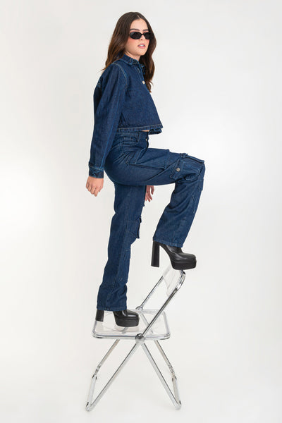 Pantalón de denim multipocket, fit recto, cintura alta con pretina y trabillas, bolsillos delanteros, laterales cargo con cartera y traseros decorativos con cartera. Cierre frontal con cremallera y botón en contraste.