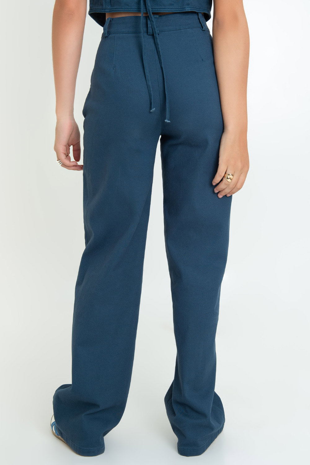Pantalón de fit recto, cintura alta con pretina y trabillas, bolsillos delanteros y vivos decorativos posteriores. Detalle de raya frontal, cierre frontal con broche y cremallera ocultos.