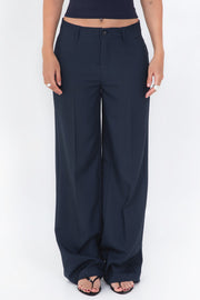 Pantalón de fit wide leg, cintura baja con pretina y trabillas, vivo decorativo posterior y detalle de raya frontal. Cierre frontal con botón y cremallera oculta.