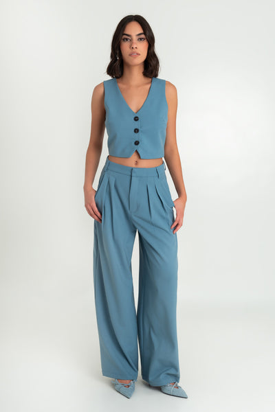 Pantalón de fit wide leg, cintura alta con pretina y trabillas, bolsillos delanteros y pinzas frontales. Cierre frontal con broche y cremallera oculta.